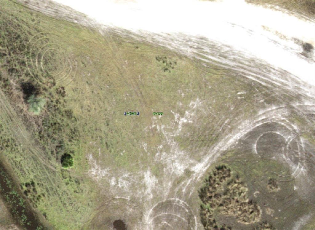 An aerial view shows a vacant, grassy plot of land with visible tire tracks — HWY 630, FROSTPROOF, FL