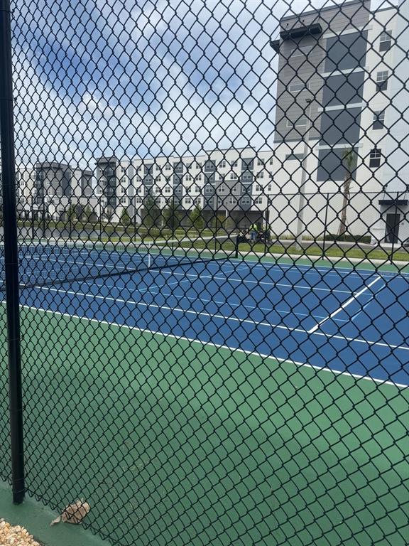 A chain-link fence overlooks a blue and green tennis court next to a large apartment building — 5579 MILLENIA PARK BOULEVARD UNIT 506, ORLANDO, FL