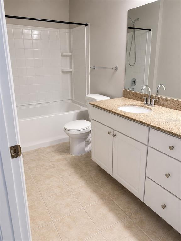 A bathroom features a white vanity with a granite countertop, a toilet, and a tub-shower — 303 SOUTHERN PECAN CIRCLE UNIT 107, WINTER GARDEN, FL