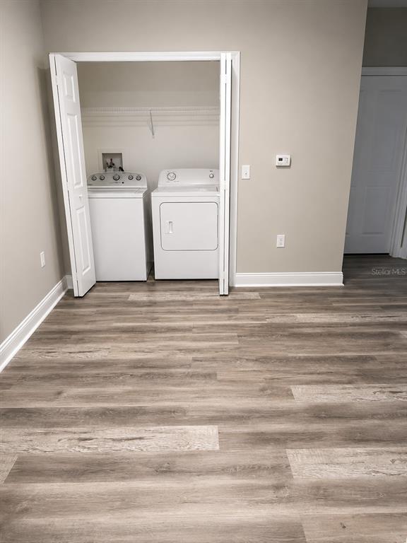 A laundry closet with a washer and dryer sits in a room with wood-look flooring — 303 SOUTHERN PECAN CIRCLE UNIT 107, WINTER GARDEN, FL