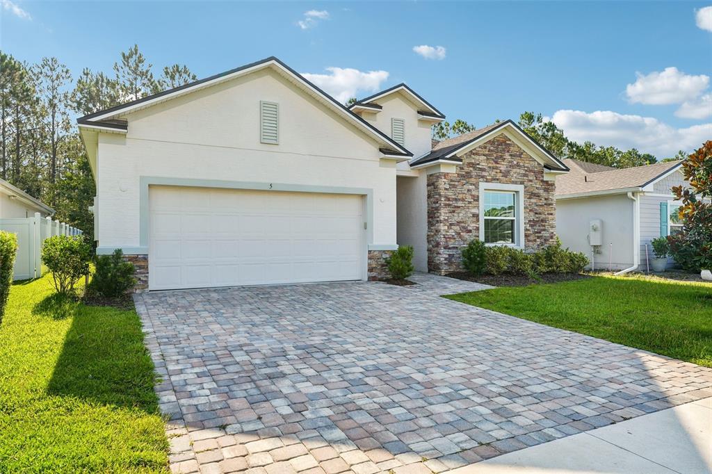 A single-story house with a white stucco facade, stone accents, and a paved driveway — 5 RIVERTOWN ROAD, PALM COAST, FL