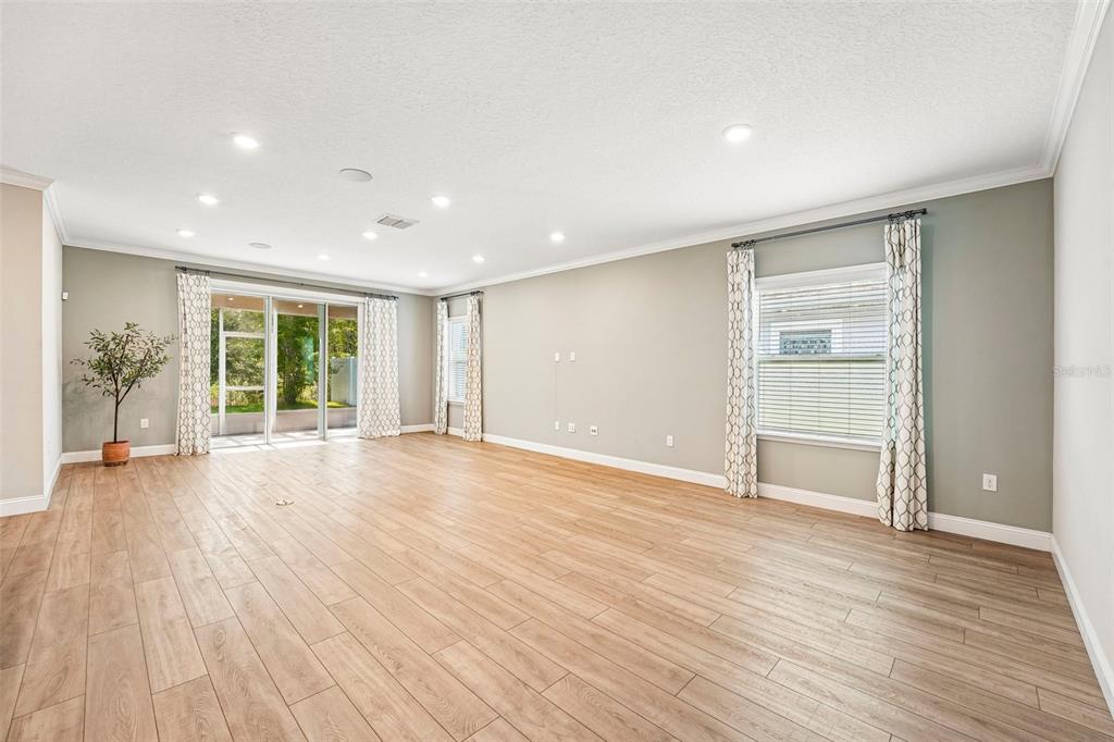 A spacious living room features light wood-look flooring, recessed lighting, and large sliding glass doors — 5 RIVERTOWN ROAD, PALM COAST, FL