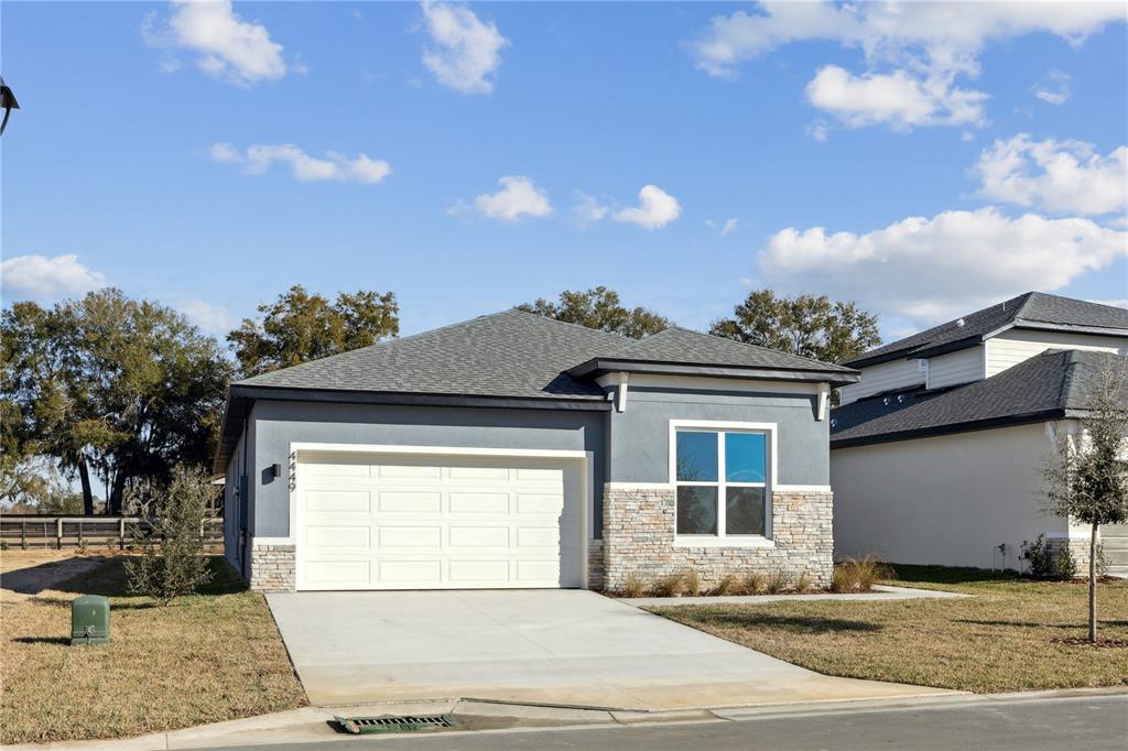 A single-story house with a two-car garage, gray stucco siding, and stone veneer accents — 82 SPRINGWOOD DRIVE, PALM COAST, FL