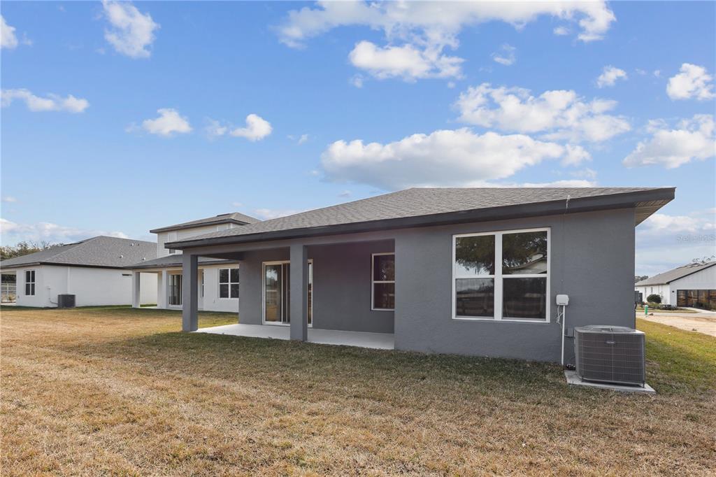 The exterior of a gray stucco house features a covered patio and an air conditioner — 82 SPRINGWOOD DRIVE, PALM COAST, FL