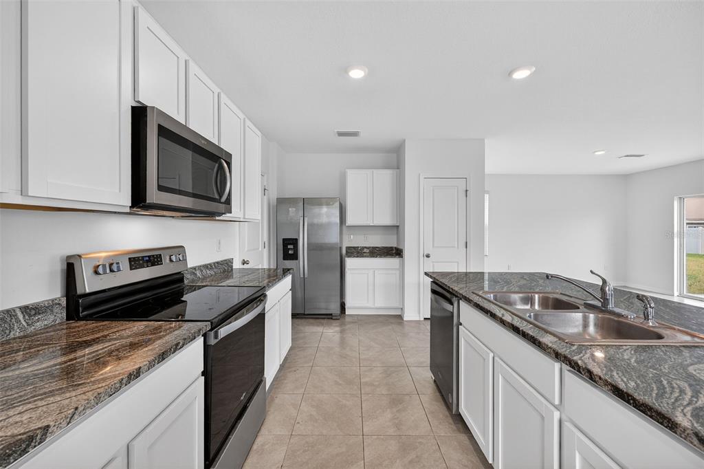 A kitchen features white cabinets, granite countertops, stainless steel appliances, and a central island — 3842 SUNNY SPRING STREET, PLANT CITY, FL