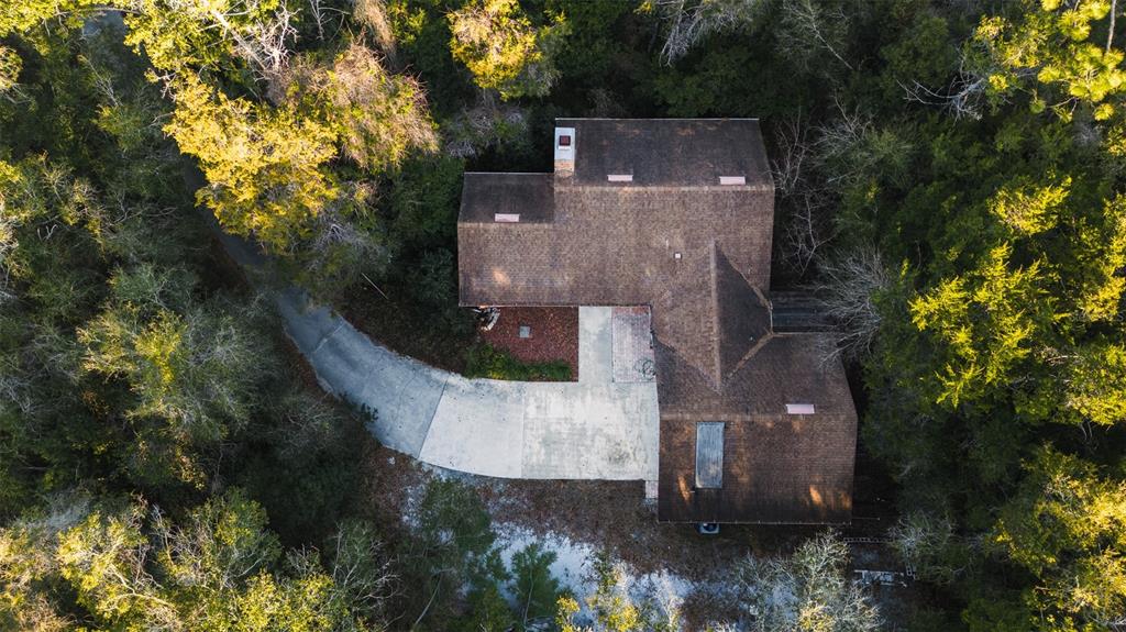 An aerial view shows a house with a brown shingled roof surrounded by dense trees — 1325 S SPRING GARDEN AVENUE, DELAND, FL