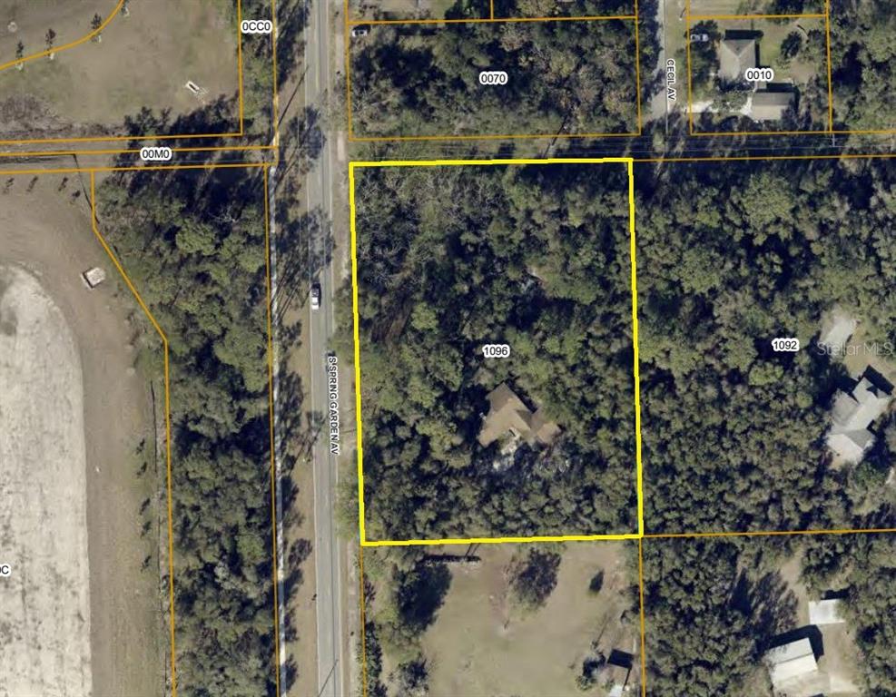 An aerial map view shows a wooded residential lot outlined in yellow along a road — 1325 S SPRING GARDEN AVENUE, DELAND, FL