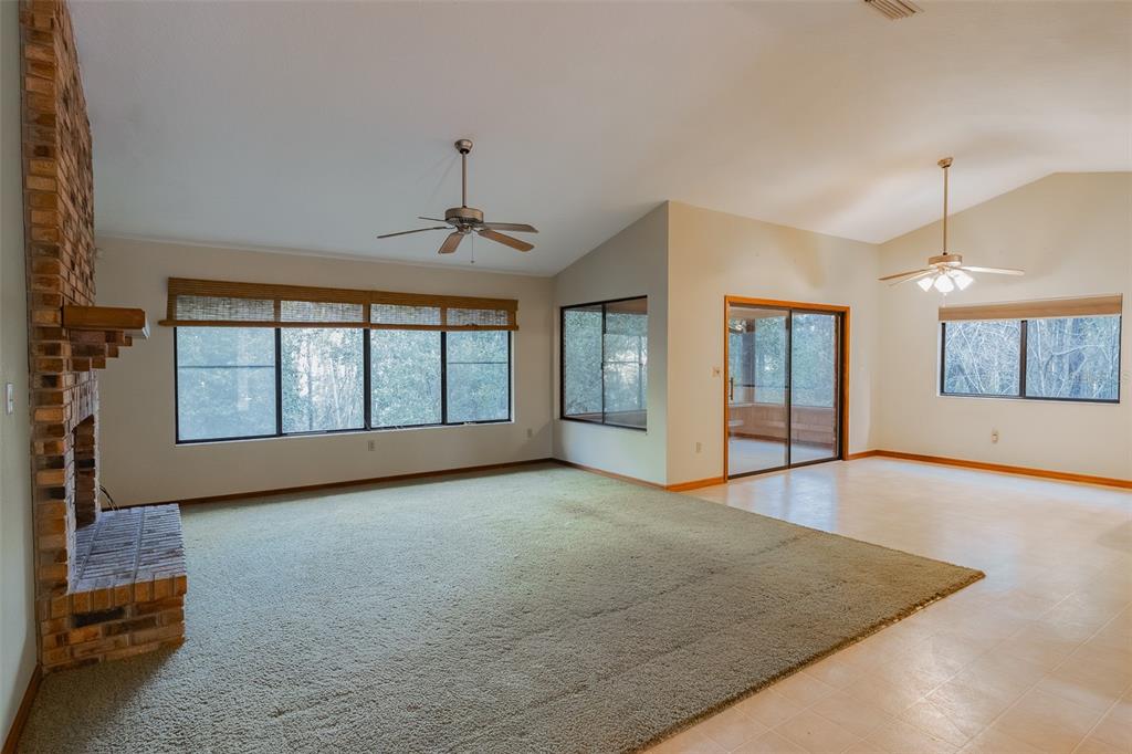 A living room features a brick fireplace, green carpeting, tile flooring, and vaulted ceilings — 1325 S SPRING GARDEN AVENUE, DELAND, FL