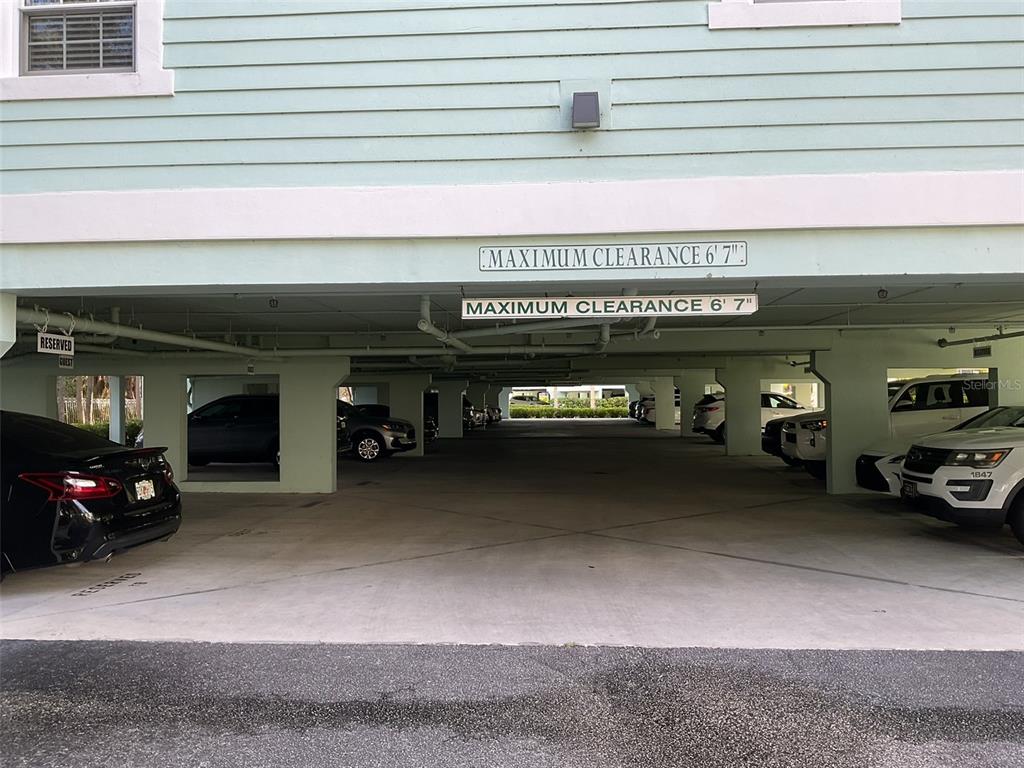 A covered parking garage features concrete pillars and multiple vehicles parked in designated spaces — 5125 MELBOURNE STREET UNIT E-305, PUNTA GORDA, FL