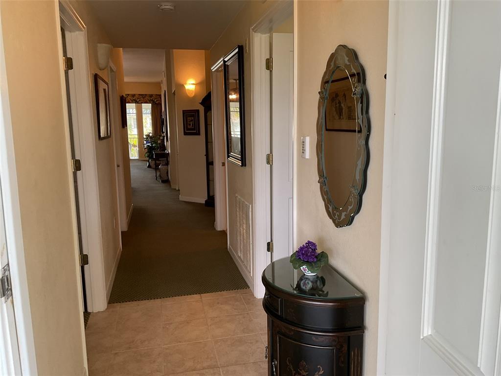 A hallway with tile flooring transitions into a carpeted corridor featuring a small accent table — 5125 MELBOURNE STREET UNIT E-305, PUNTA GORDA, FL