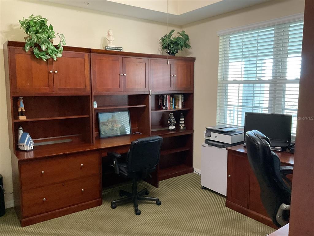 A dining area features a round wooden table with leather chairs and a glass-front hutch — 5125 MELBOURNE STREET UNIT E-305, PUNTA GORDA, FL