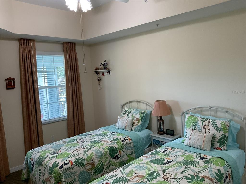 A living room with a brown sofa, dining area, ceiling fan, and sliding glass balcony doors — 5125 MELBOURNE STREET UNIT E-305, PUNTA GORDA, FL