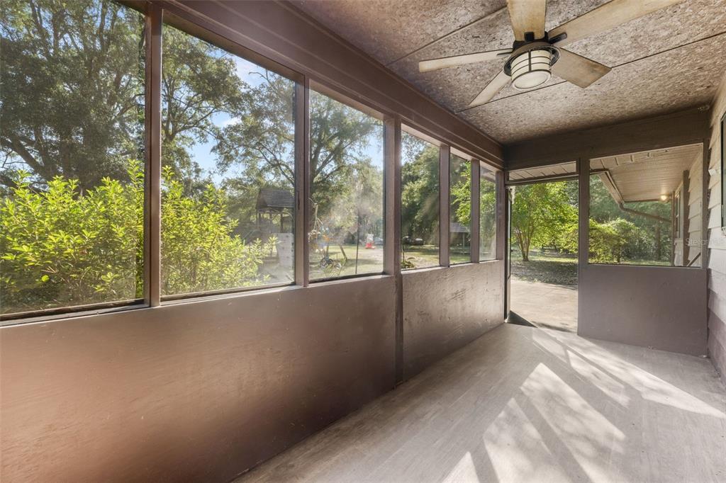 A screened-in porch with a ceiling fan, wood-look flooring, and views of a backyard — 79 NW 55TH AVENUE, BELL, FL