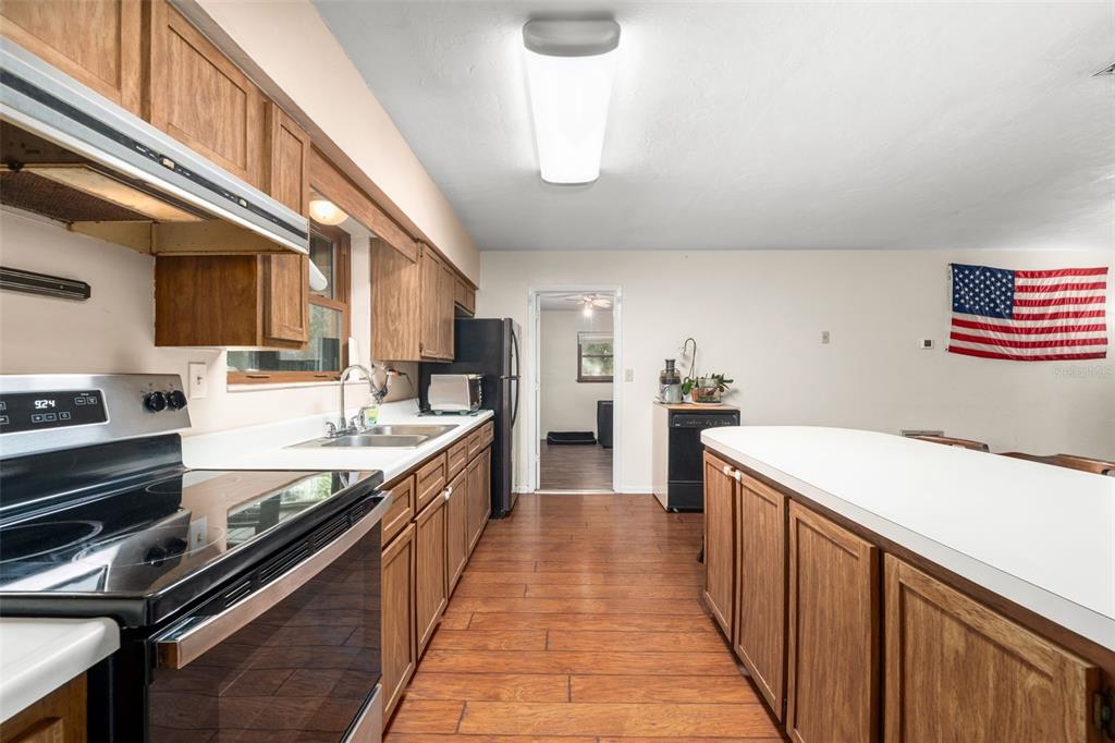 A kitchen features wood cabinets, a white countertop island, and a black range — 79 NW 55TH AVENUE, BELL, FL