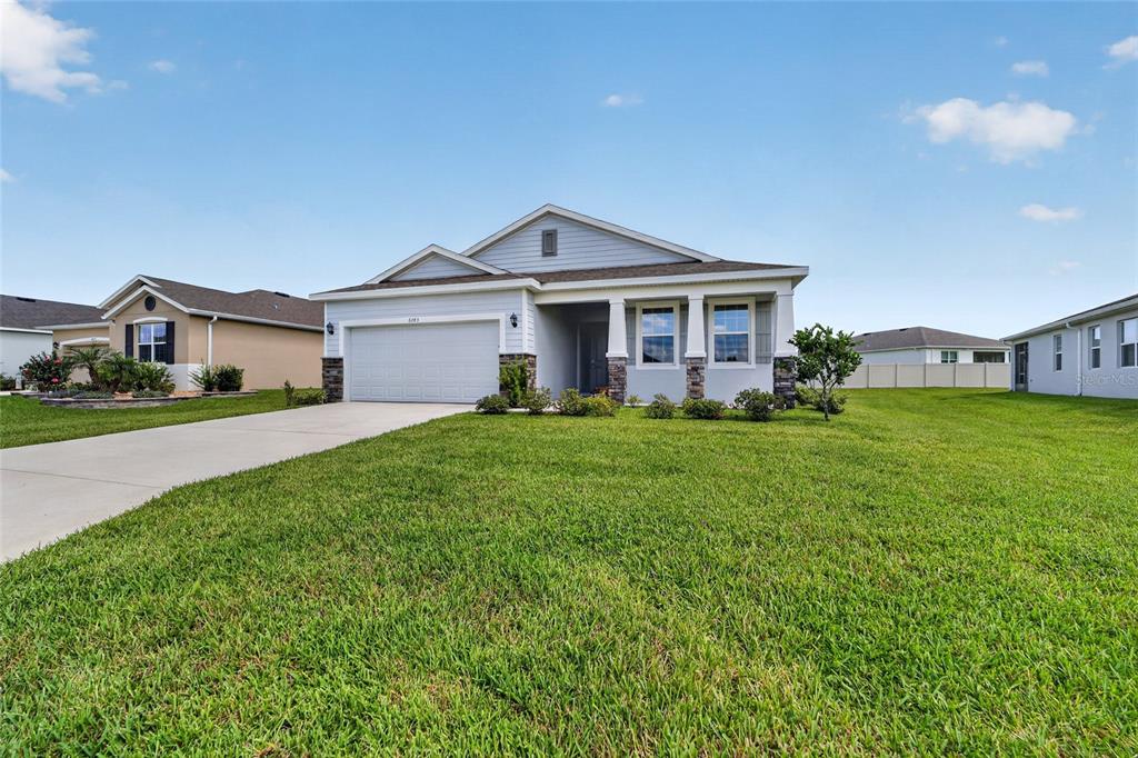 A single-story suburban house with a two-car garage, light siding, and a front porch — 6083 SW 93RD LOOP, OCALA, FL