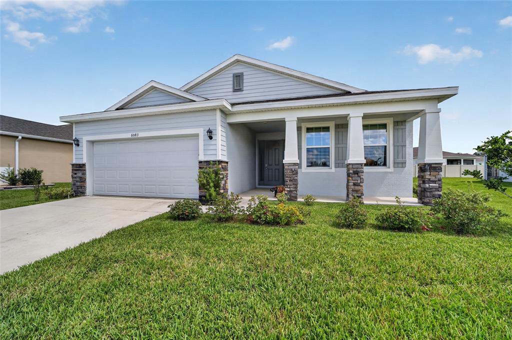 A single-story house with light blue siding, a two-car garage, and a covered front porch — 6083 SW 93RD LOOP, OCALA, FL