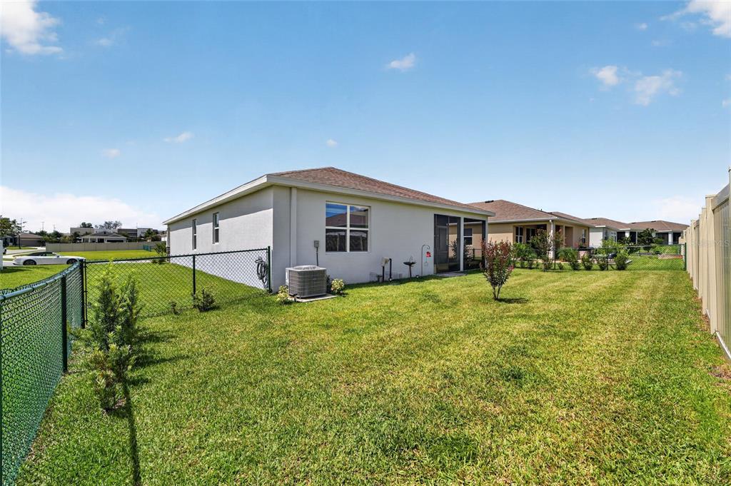 The backyard features a grassy lawn, a chain-link fence, and the rear exterior of a house — 6083 SW 93RD LOOP, OCALA, FL