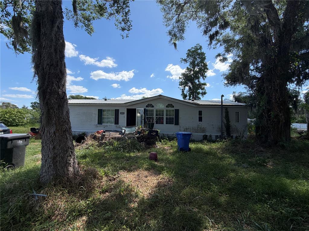 A single-story manufactured home sits on a grassy lot with large trees — 11316 MCMULLEN ROAD, RIVERVIEW, FL