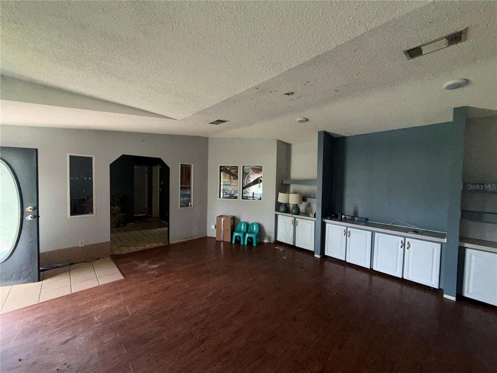 A living room with dark wood flooring, white cabinetry, and a dark blue accent wall — 11316 MCMULLEN ROAD, RIVERVIEW, FL