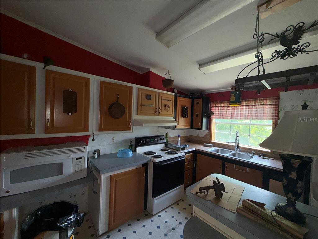 A kitchen features wood-trimmed cabinets, red walls, a white stove, and a double sink — 11316 MCMULLEN ROAD, RIVERVIEW, FL