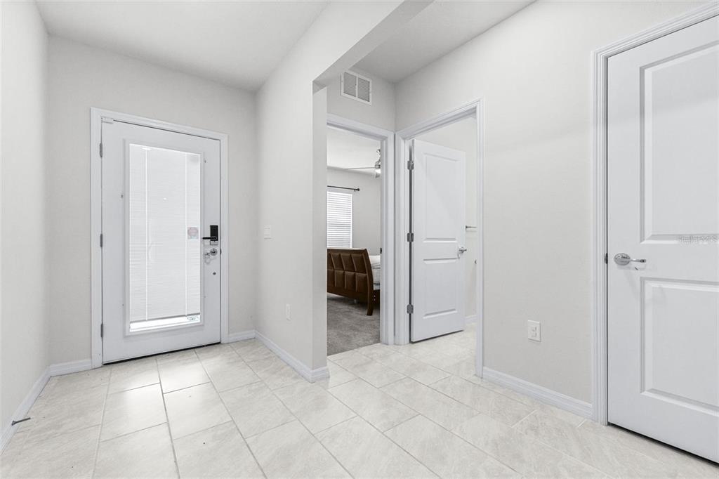 A bright entryway with light tile flooring, a glass-paneled front door, and interior doors — 1050 MICHELANGELO LANE, WINTER HAVEN, FL