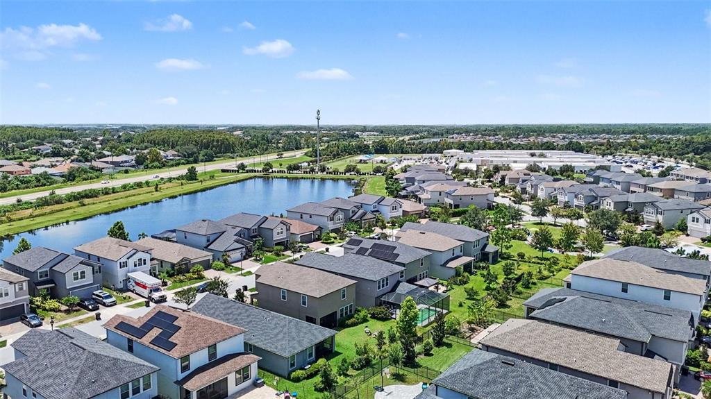 An aerial view shows a suburban neighborhood with houses surrounding a central retention pond — 17989 FRAME BEND, LAND O LAKES, FL