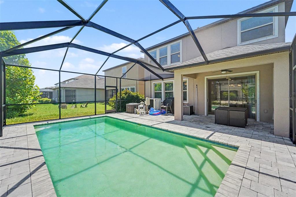 A backyard swimming pool with a screened enclosure and a paved patio area — 17989 FRAME BEND, LAND O LAKES, FL