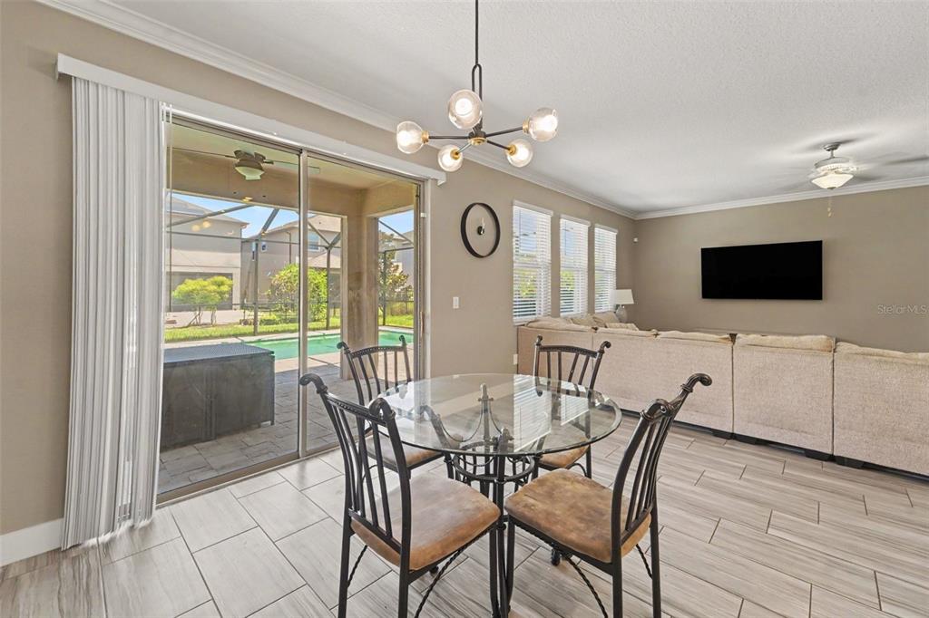 A dining area with a glass table and chairs sits beside a sliding door to a pool — 17989 FRAME BEND, LAND O LAKES, FL