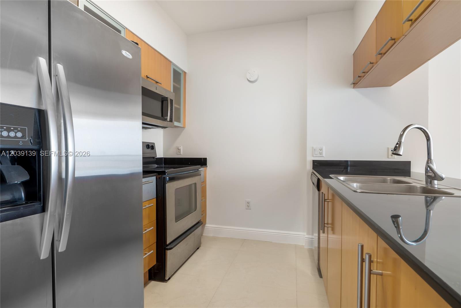 A kitchen features stainless steel appliances, light wood cabinets, and black countertops — 1750 N Bayshore Dr # 4811, Miami FL 33132, MIAMI, FL