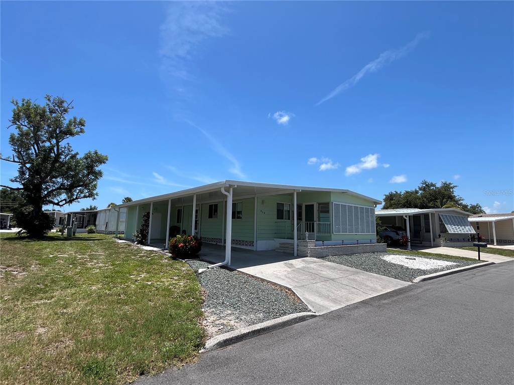 A light green mobile home with a covered carport and a concrete driveway — 958 CORTINA BOULEVARD, VENICE, FL