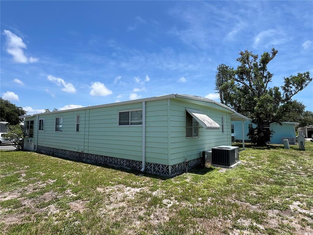 The exterior of a light green mobile home features horizontal siding and a metal awning — 958 CORTINA BOULEVARD, VENICE, FL