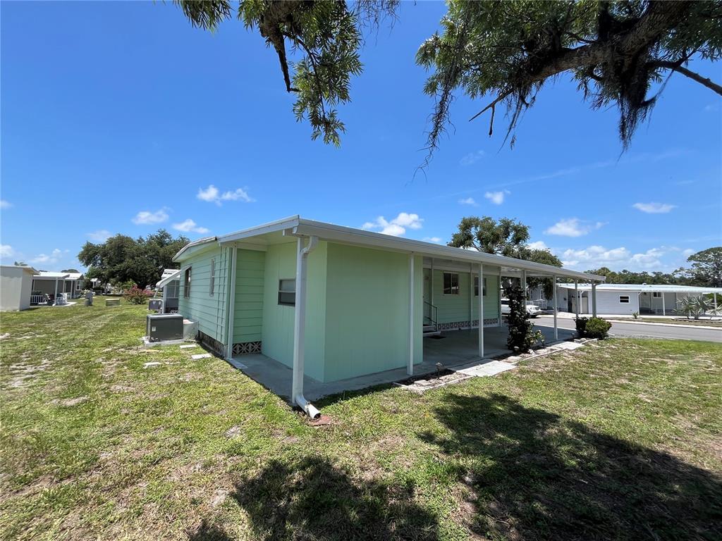 A light green mobile home with a covered porch sits on a grassy lot — 958 CORTINA BOULEVARD, VENICE, FL