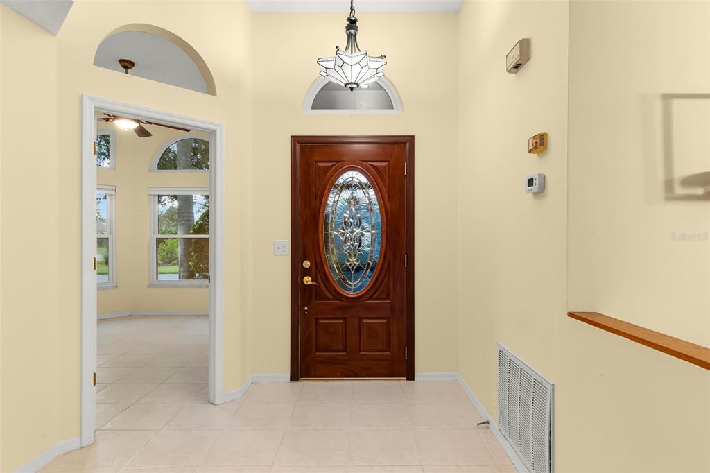 A foyer features a wooden front door with a glass insert, tile flooring, and light walls — 1601 LAUGHTON PLACE, SUN CITY CENTER, FL