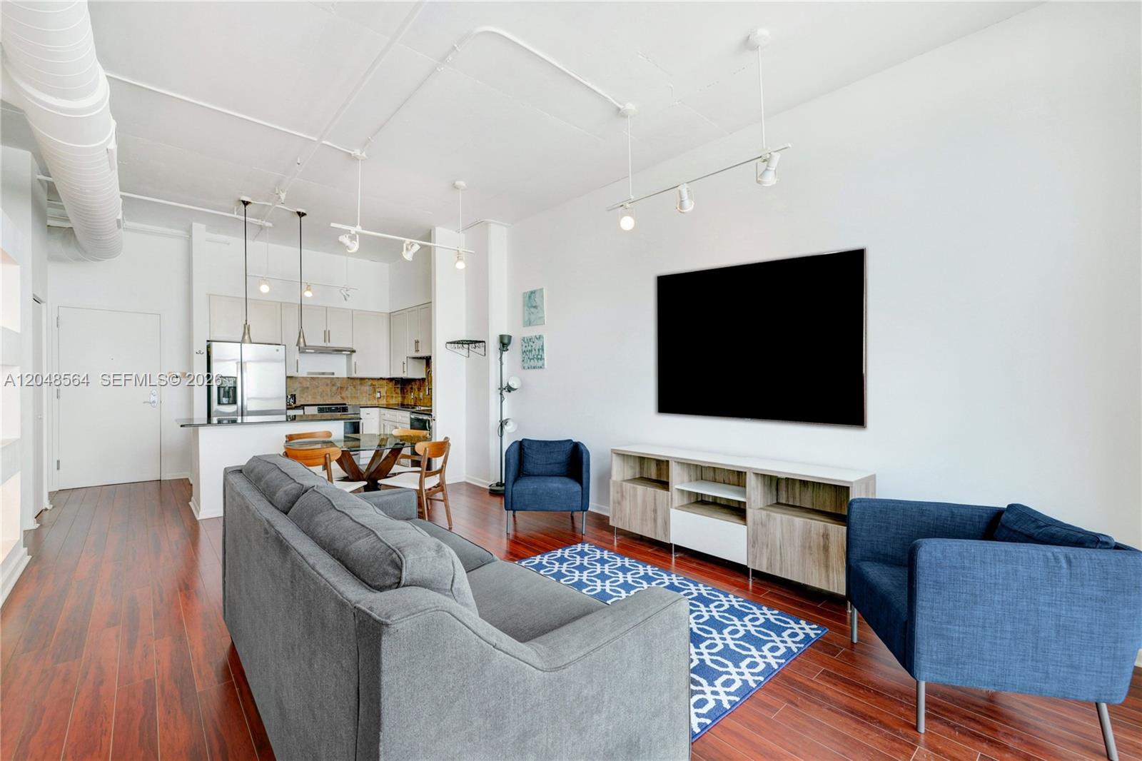 A living room with a grey sofa, two blue armchairs, and an open kitchen — 2001 Biscayne Blvd # 2514, Miami FL 33137, MIAMI, FL