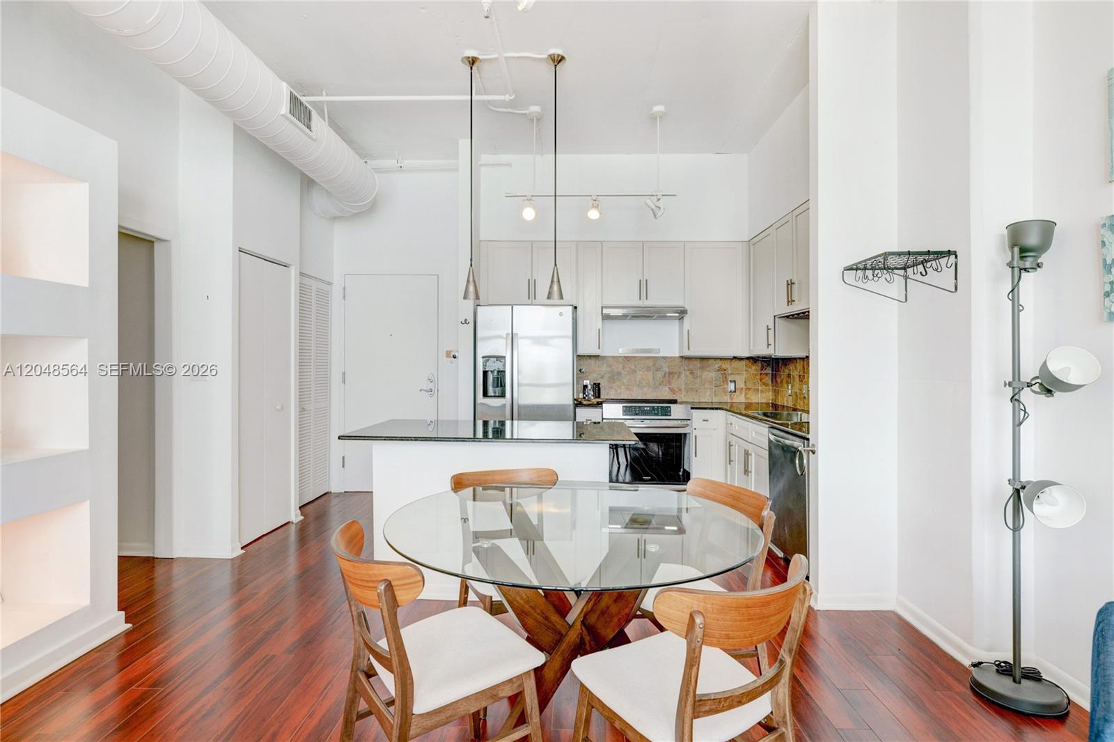 A kitchen with white cabinets and a glass-topped dining table on hardwood floors — 2001 Biscayne Blvd # 2514, Miami FL 33137, MIAMI, FL