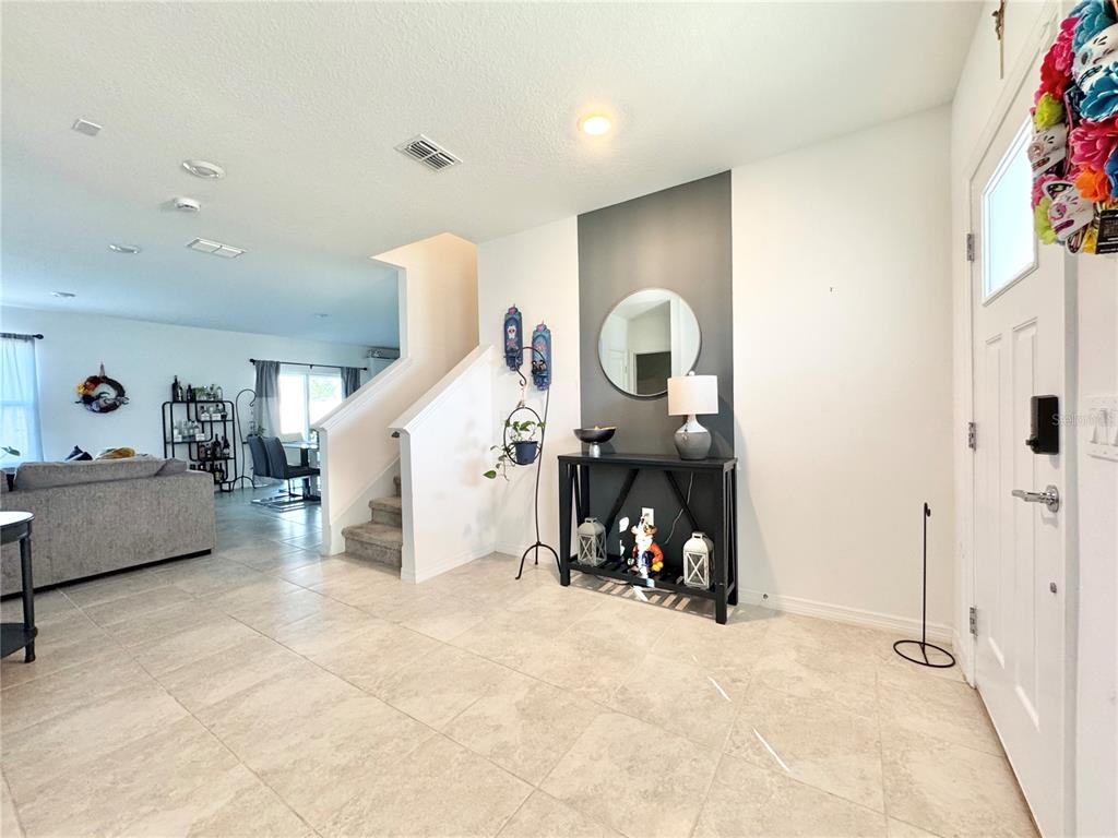 An entryway features tile flooring, a dark accent wall with a mirror, and a console table — 557 PINE TREE BOULEVARD, LAKE ALFRED, FL