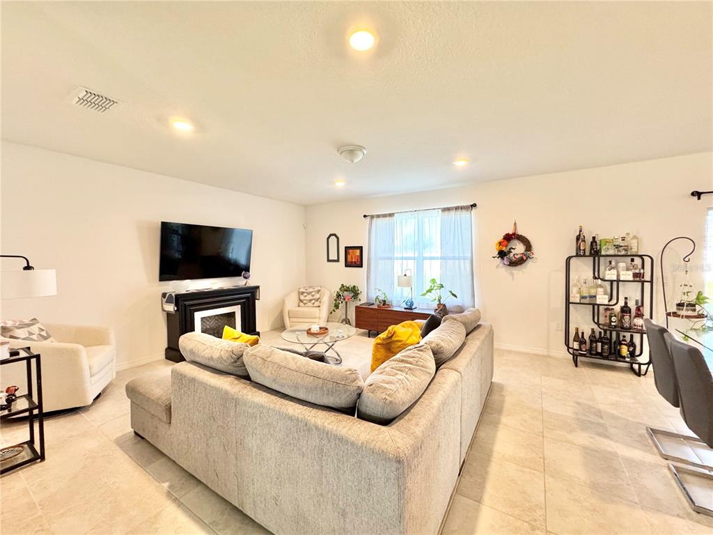 A living room features a sectional sofa, a fireplace with a television, and tile flooring — 557 PINE TREE BOULEVARD, LAKE ALFRED, FL