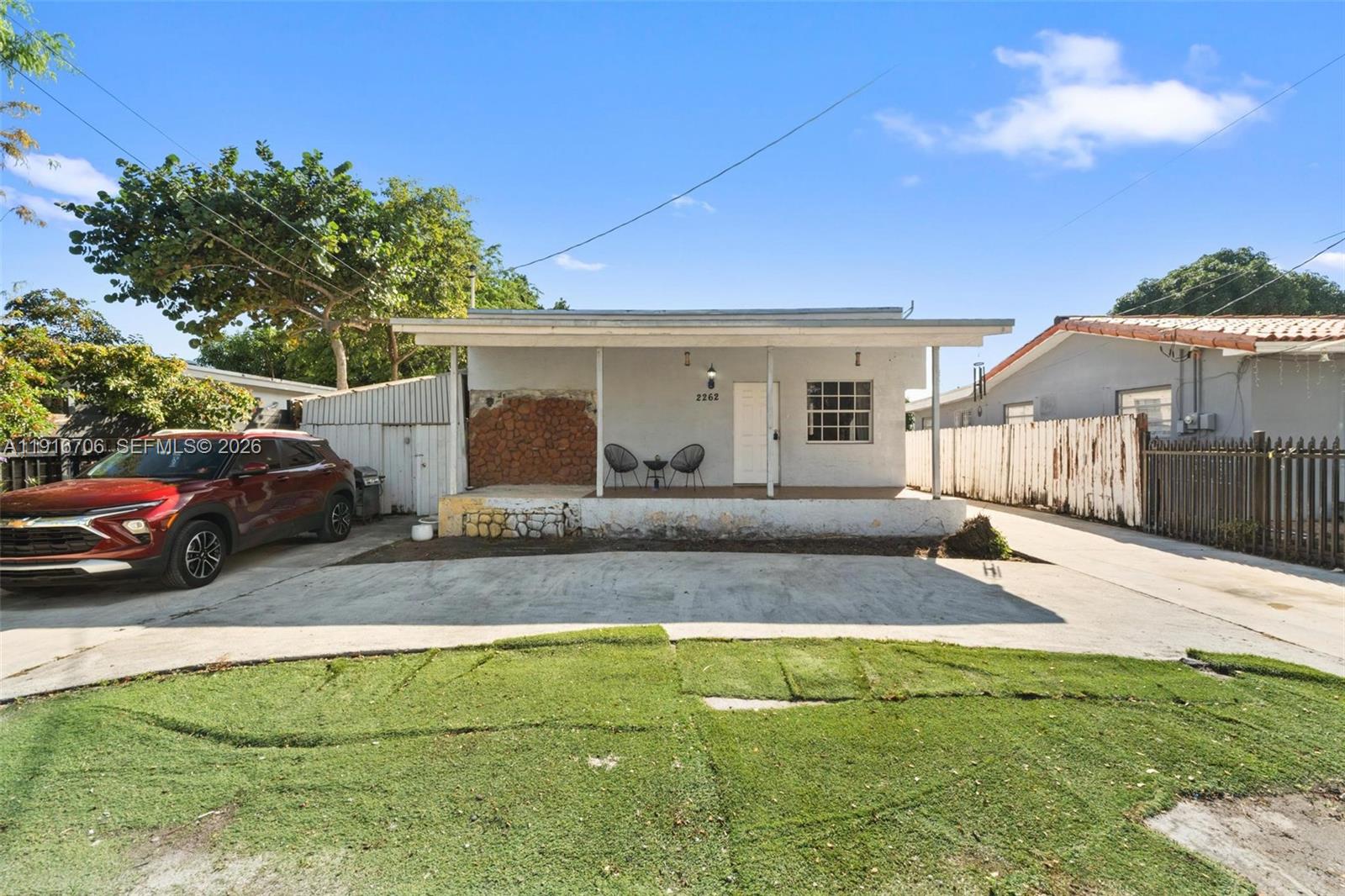 A single-story house features a covered front porch, a concrete driveway, and a red car — 2262 NW 4th St, Miami FL 33125, MIAMI, FL