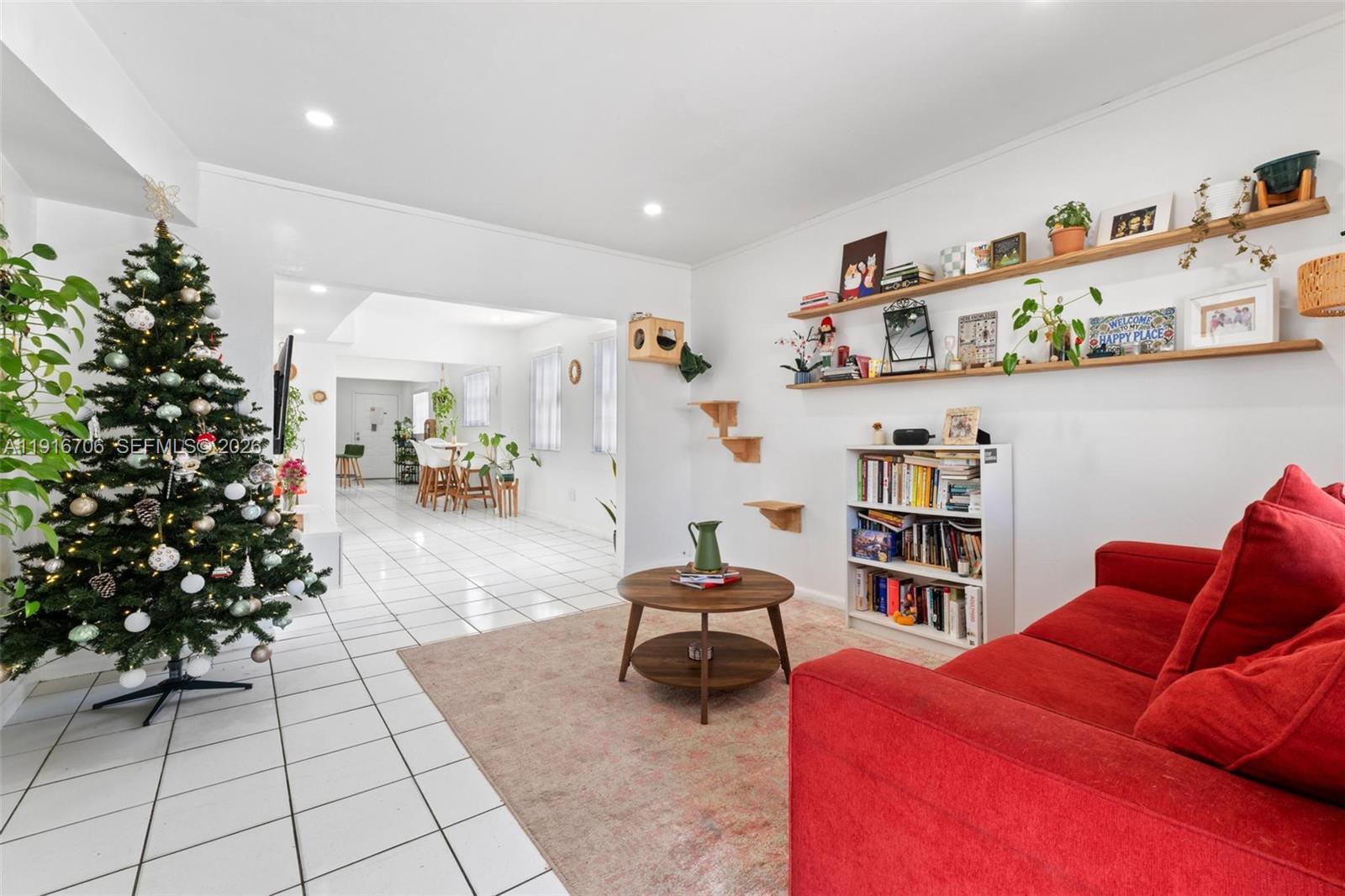 A living room features a Christmas tree, a red sofa, wall shelves, and tiled floors — 2262 NW 4th St, Miami FL 33125, MIAMI, FL