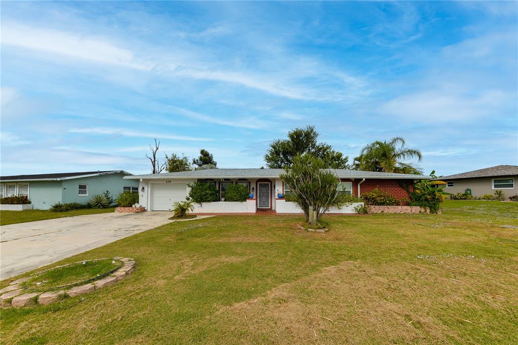 A single-story house with a brick facade, white trim, and a concrete driveway — 124 CADDY ROAD, ROTONDA WEST, FL
