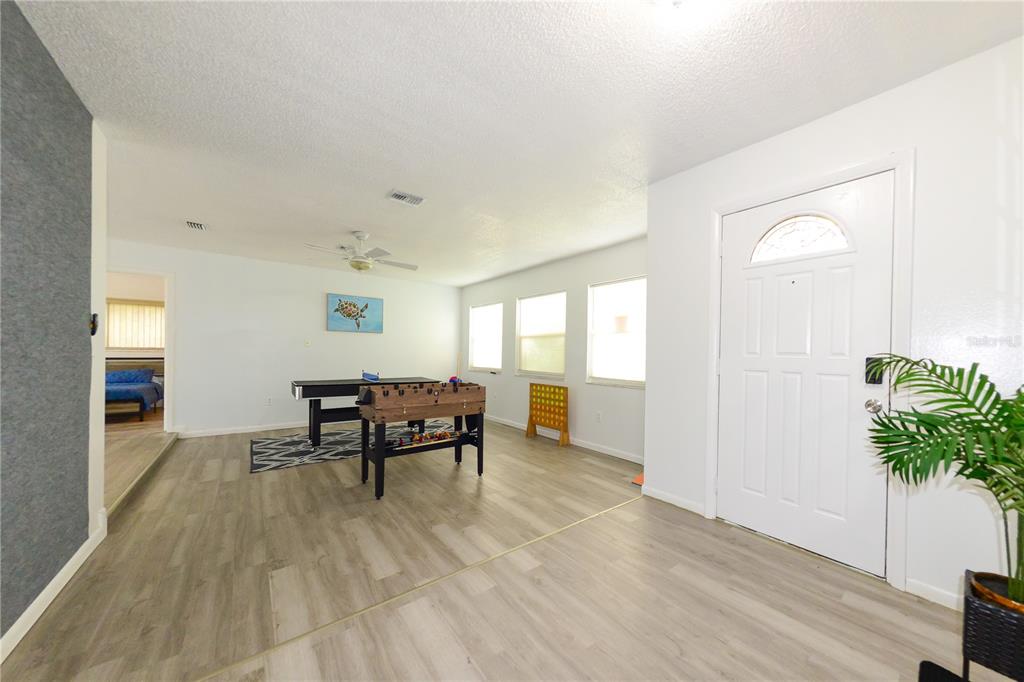 A game room features light wood-look flooring, a foosball table, and a white front door — 124 CADDY ROAD, ROTONDA WEST, FL