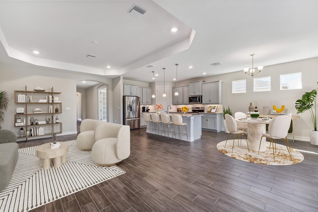An open-concept kitchen, dining area, and living room feature gray cabinetry and wood-look tile flooring — 12718 SEAGRASS DRIVE, PUNTA GORDA, FL