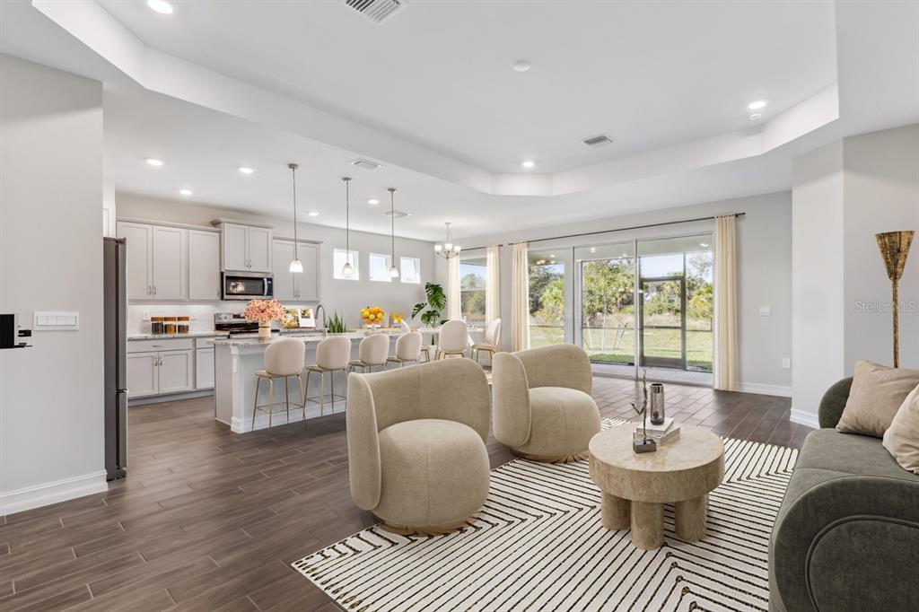 An open-concept kitchen and living area features light cabinetry, a kitchen island, and sliding doors — 12718 SEAGRASS DRIVE, PUNTA GORDA, FL