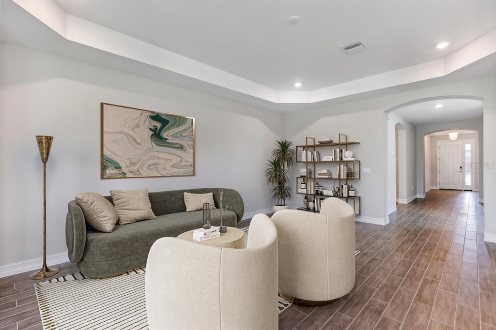 A living room features a grey sofa, two cream armchairs, a bookshelf, and tile flooring — 12718 SEAGRASS DRIVE, PUNTA GORDA, FL