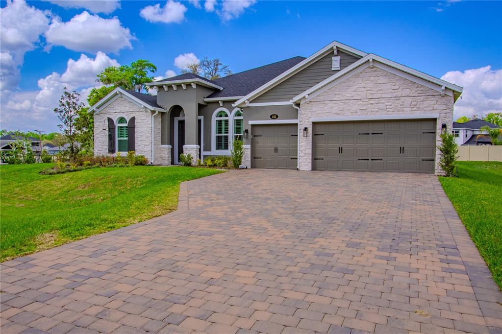 A single-story house with a stone and siding exterior, a three-car garage, and a paver driveway — 132 LAKE DRIVE, OVIEDO, FL