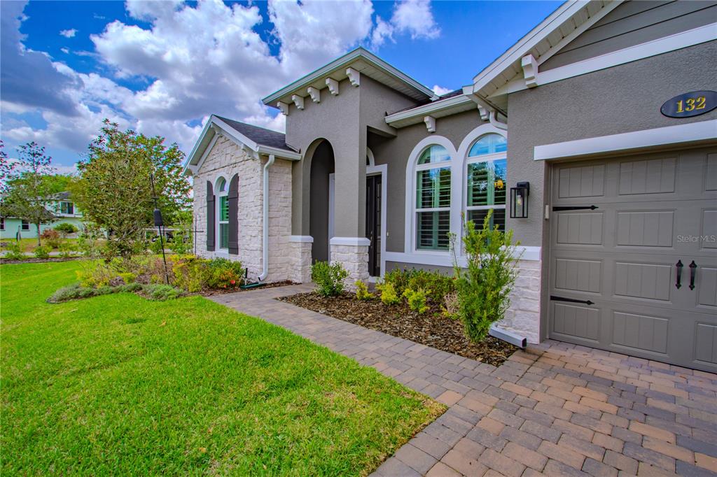 A single-story house exterior features a stone facade, arched windows, and a paved walkway — 132 LAKE DRIVE, OVIEDO, FL