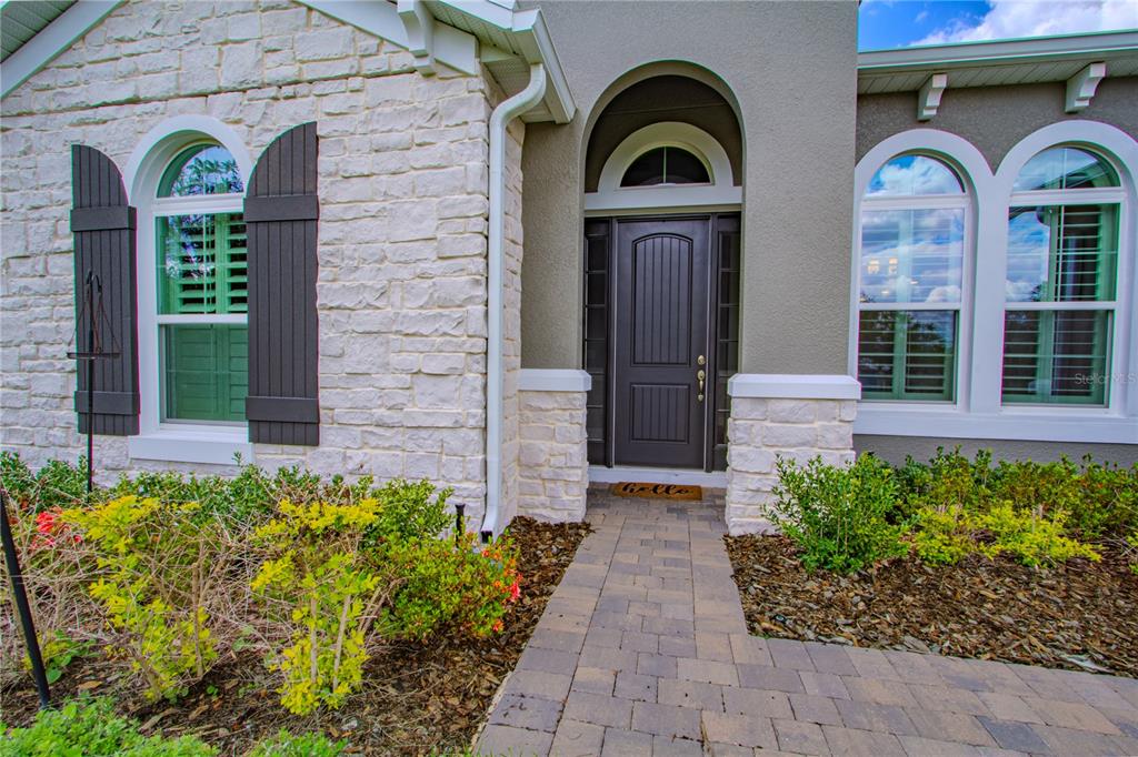The exterior of a house features a stone facade, a dark front door, and shutters — 132 LAKE DRIVE, OVIEDO, FL