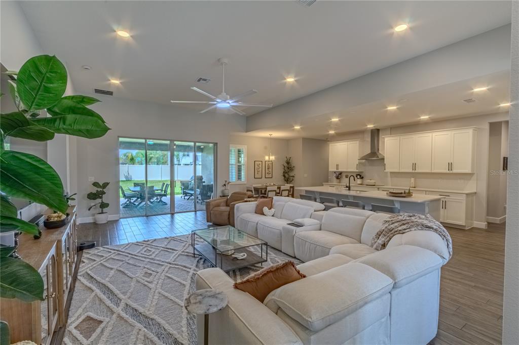 An open-concept living room and kitchen feature white cabinetry, a large sectional, and sliding doors — 132 LAKE DRIVE, OVIEDO, FL