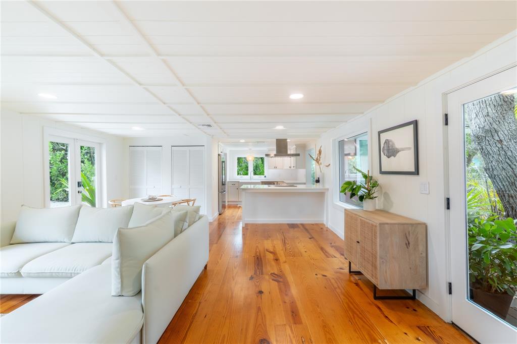 A bright living room and kitchen area features white walls, wood floors, and glass doors — 3001 51ST STREET S, GULFPORT, FL