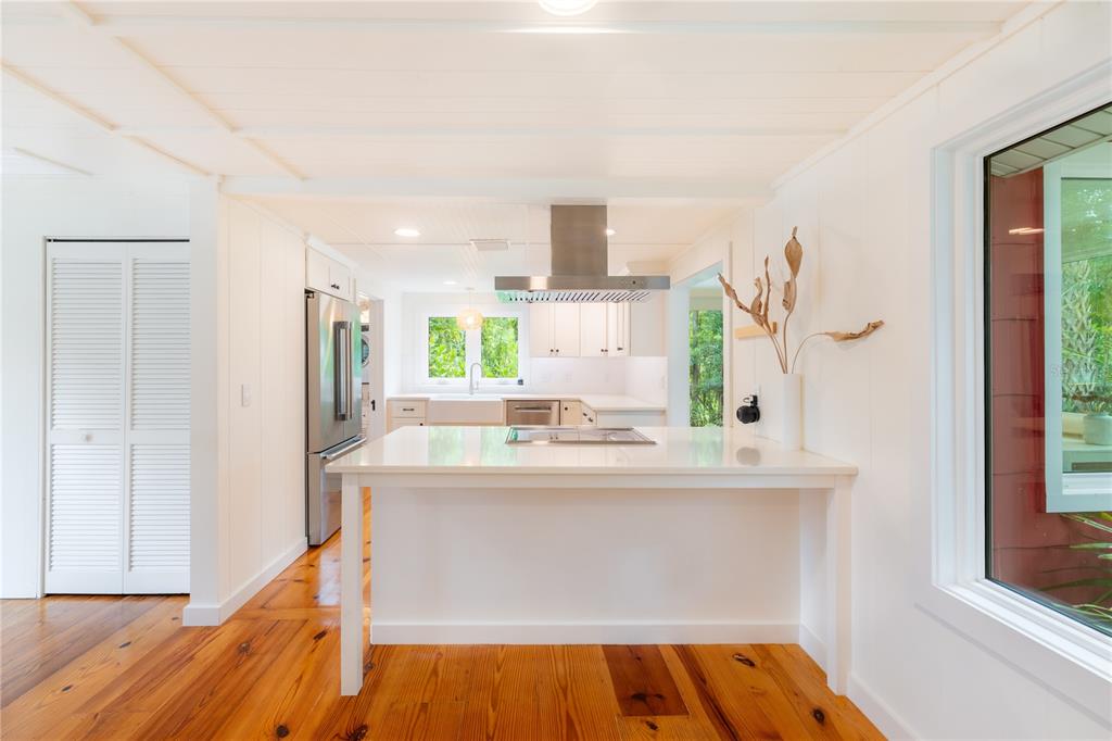A kitchen with a white island, stainless steel range hood, and natural wood flooring — 3001 51ST STREET S, GULFPORT, FL